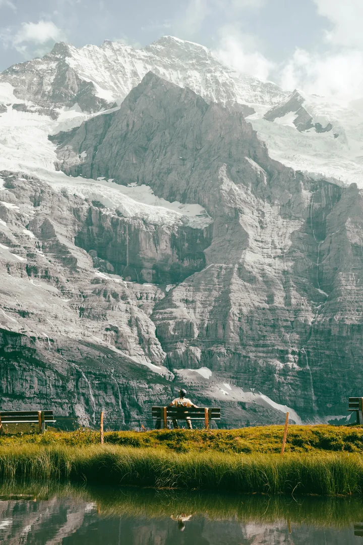 A glacier-covered mountain above a lake and benches