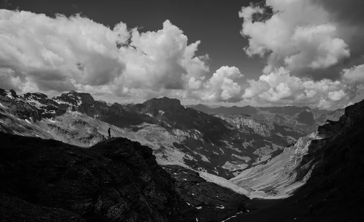 Black-and-white mountain valley under heavy clouds
